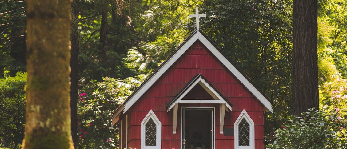 Red Chapel on Grassy Field With Trees