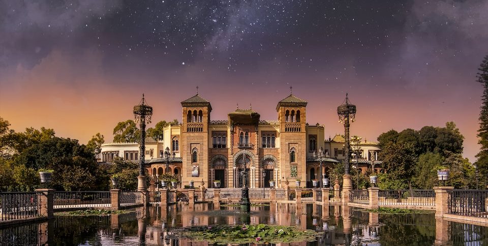 a large building sitting on top of a lake under a night sky