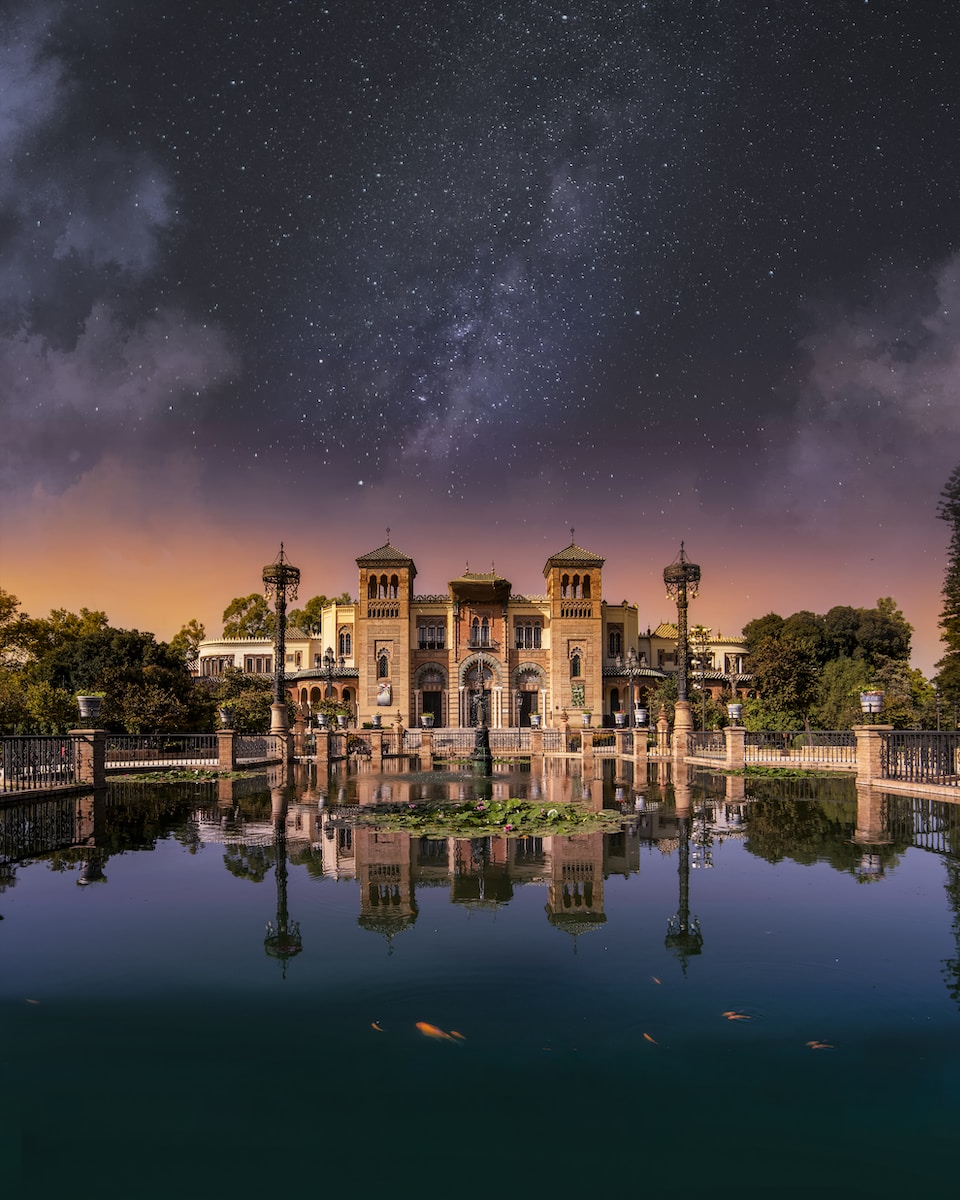 a large building sitting on top of a lake under a night sky