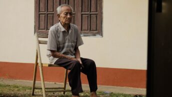 Photo of Elderly Man Sitting on Wooden Chair Outside House