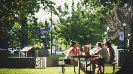 Three Women Sitting On Benches