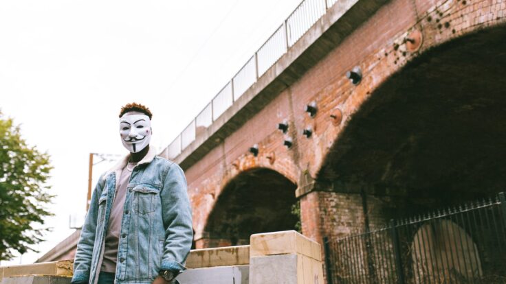 Faceless black man in mask of anonymous on street